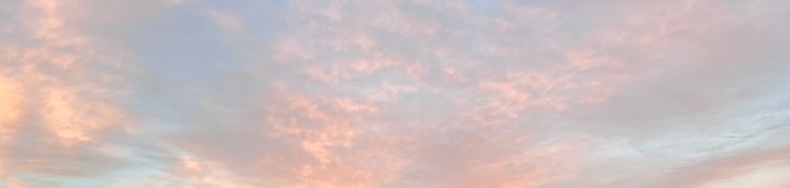 Fluffy, sparse salmon pink-ish clouds at dusk over a light blue sky, getting darker.